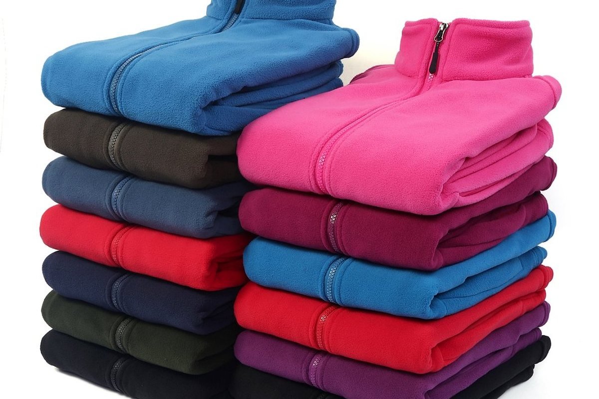 Stacked fleece jackets from a finished production run - Custom Softshell Jacket Manufacturer: 2026 Guide