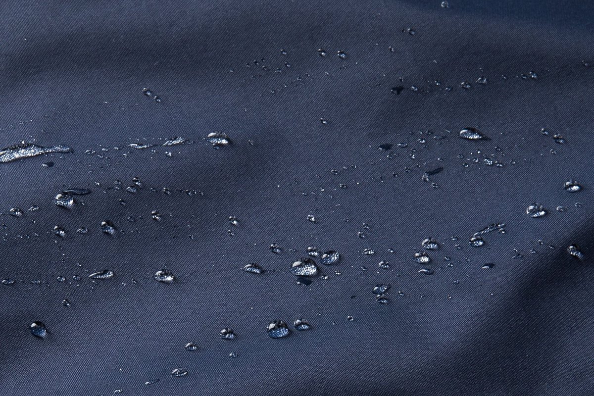 Water beading on the shell face of a navy vest - DWR Treatment Explained: C0 vs C6 vs C8 (PFC-Free Guide)